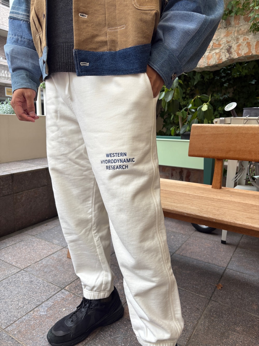 ブルー系のデニムジャケット、ブラック系のニット/セーター、ホワイト系のその他パンツを着用したメンズの秋コーディネートの4枚目の写真