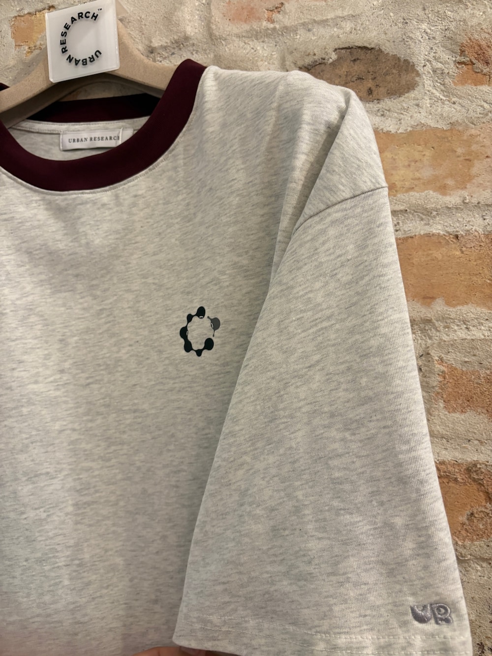 レッド系のトートバッグ、その他のデニムパンツ、ベージュ系のTシャツ/カットソーを着用したメンズの夏コーディネートの2枚目の写真