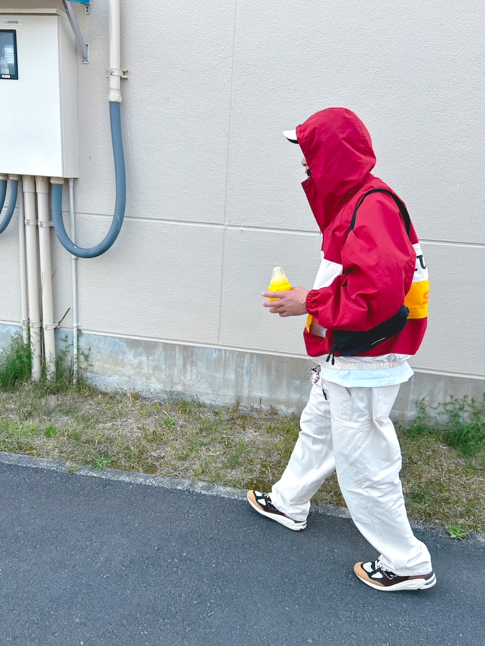 レッド系のブルゾン、ホワイト系のチノパンツ、ブラウン系のスニーカーを着用したメンズの春コーディネートの2枚目の写真