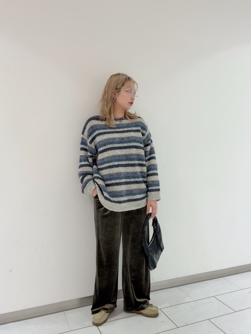 ブルー系のニット/セーター、ブラック系のハンドバッグ、シルバー系のメガネを着用したレディースの冬コーディネートの4枚目の写真