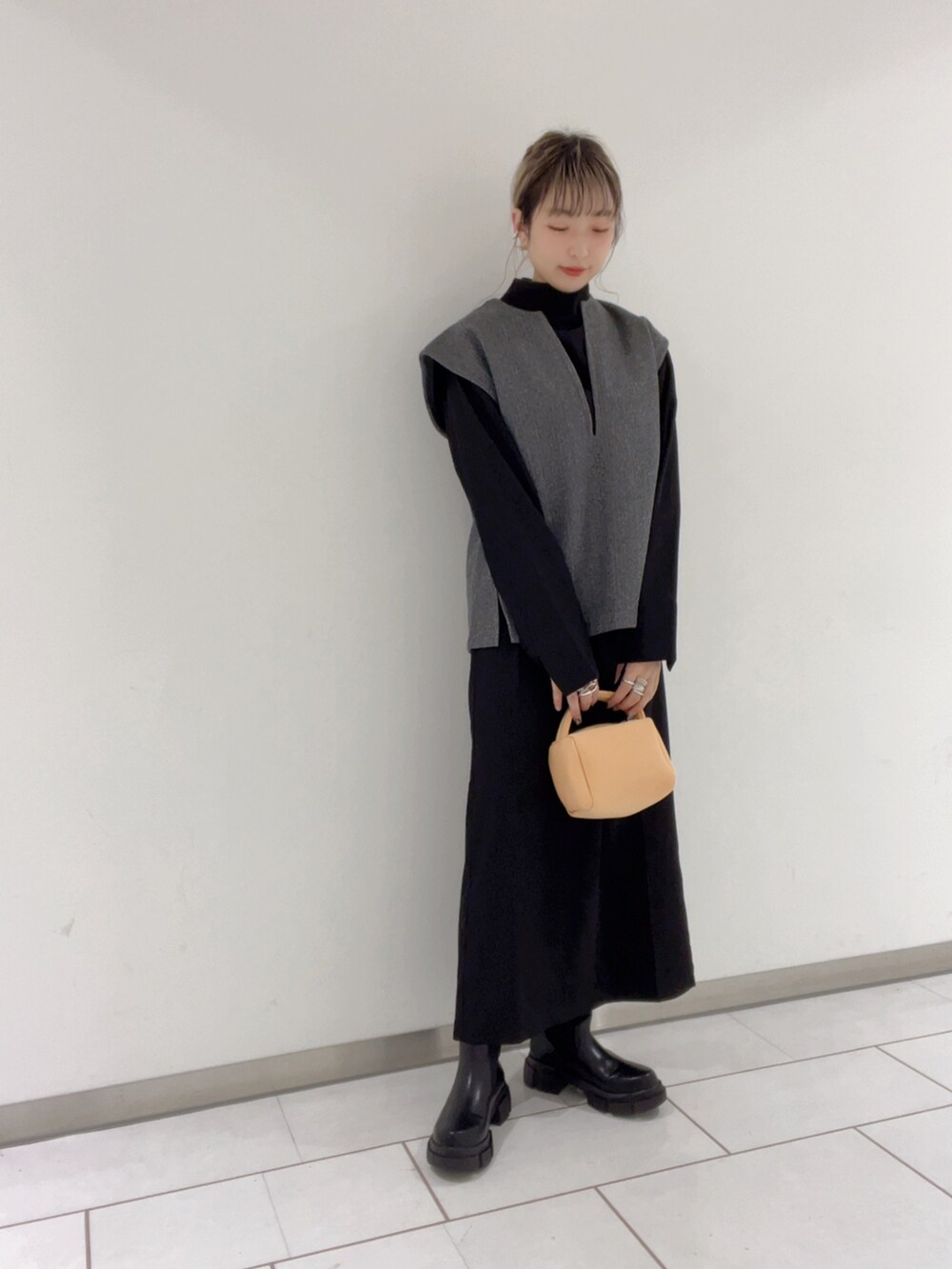 グレー系のベスト、ブラック系のワンピースを着用したレディースの冬コーディネートの2枚目の写真