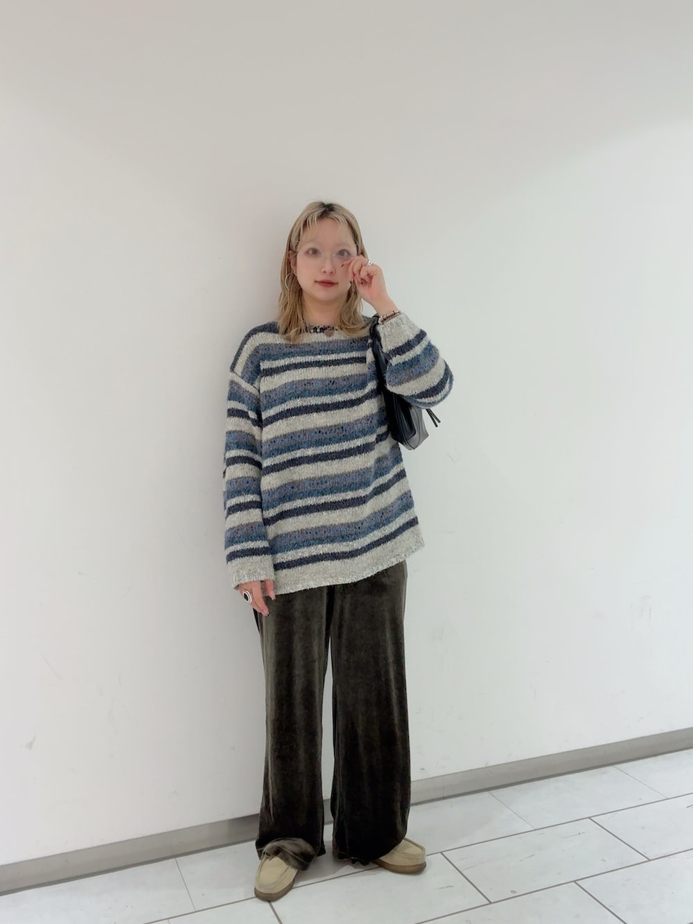 ブルー系のニット/セーター、ブラック系のハンドバッグ、シルバー系のメガネを着用したレディースの冬コーディネートの2枚目の写真