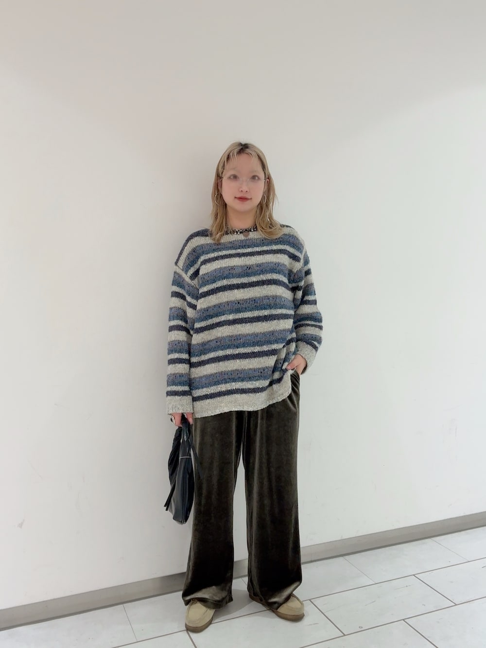 ブルー系のニット/セーター、ブラック系のハンドバッグ、シルバー系のメガネを着用したレディースの冬コーディネートの3枚目の写真