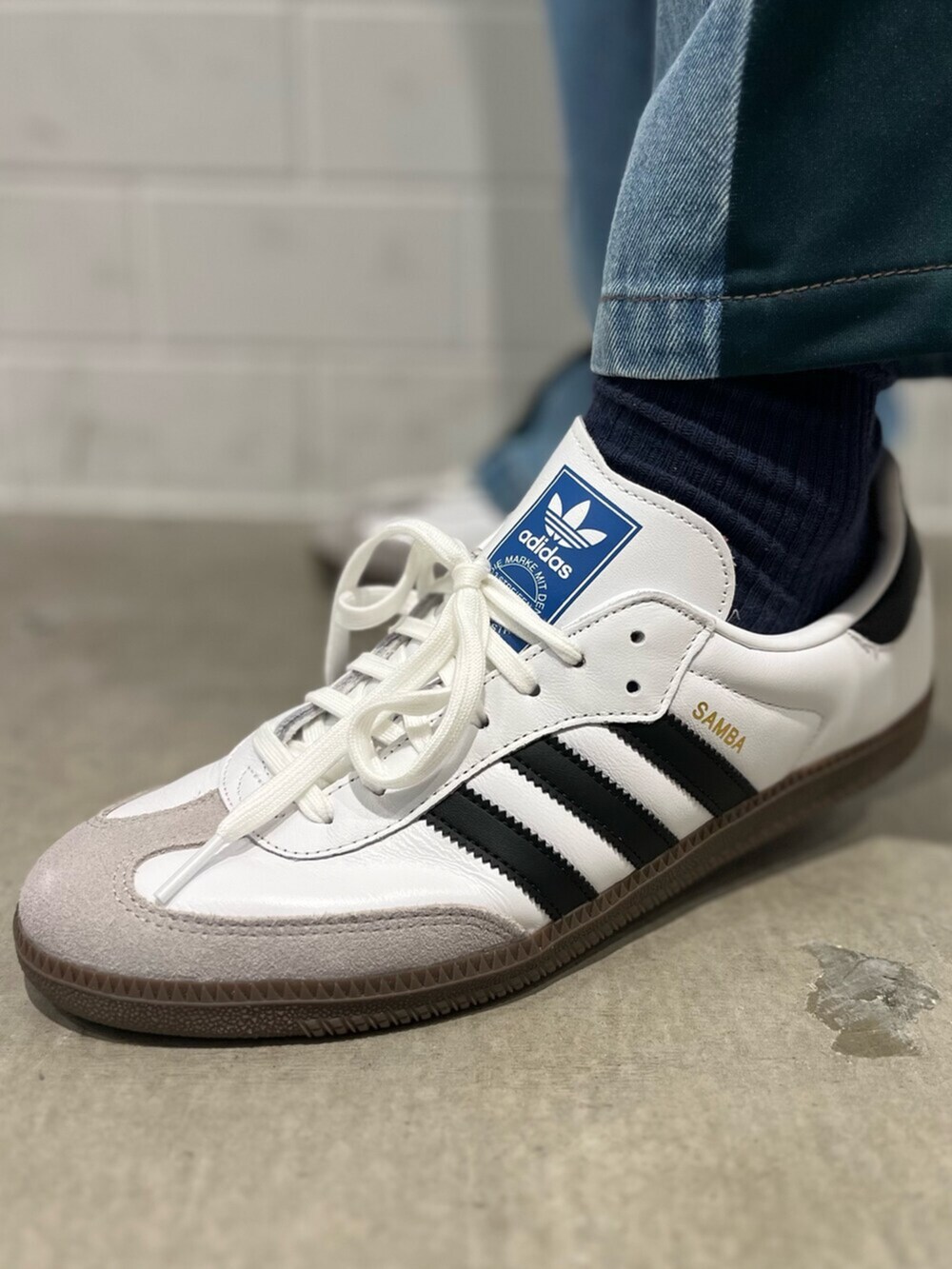 ホワイト系のジャージ、ブルー系のデニムパンツ、ブラック系のショルダーバッグを着用したメンズの秋コーディネートの6枚目の写真