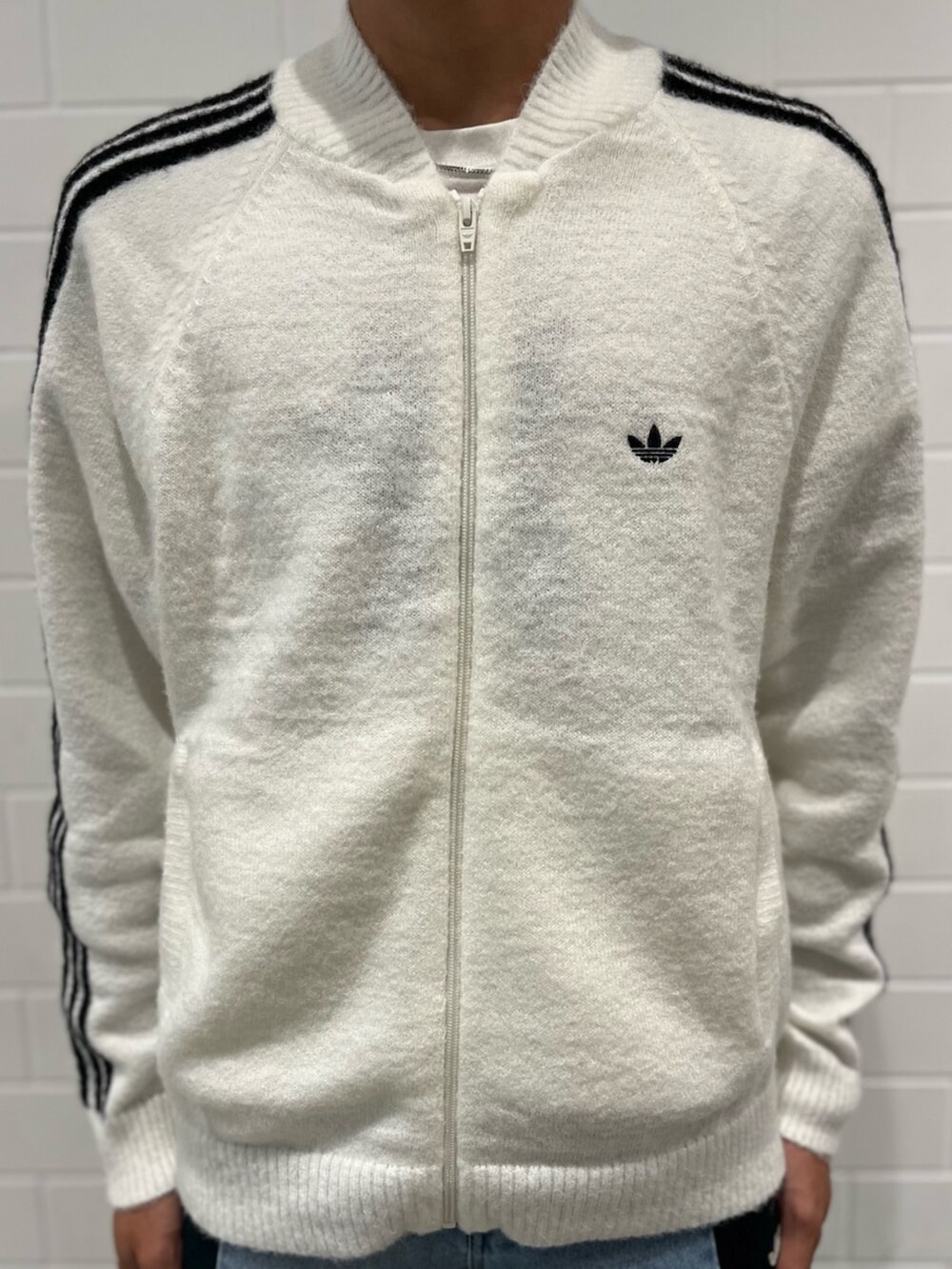 ホワイト系のジャージ、ブルー系のデニムパンツ、ブラック系のショルダーバッグを着用したメンズの秋コーディネートの3枚目の写真