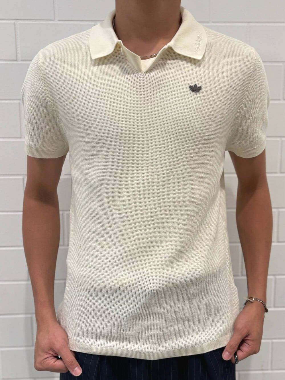 ホワイト系のポロシャツ、ブラック系のスニーカーを着用したメンズの秋コーディネートの3枚目の写真