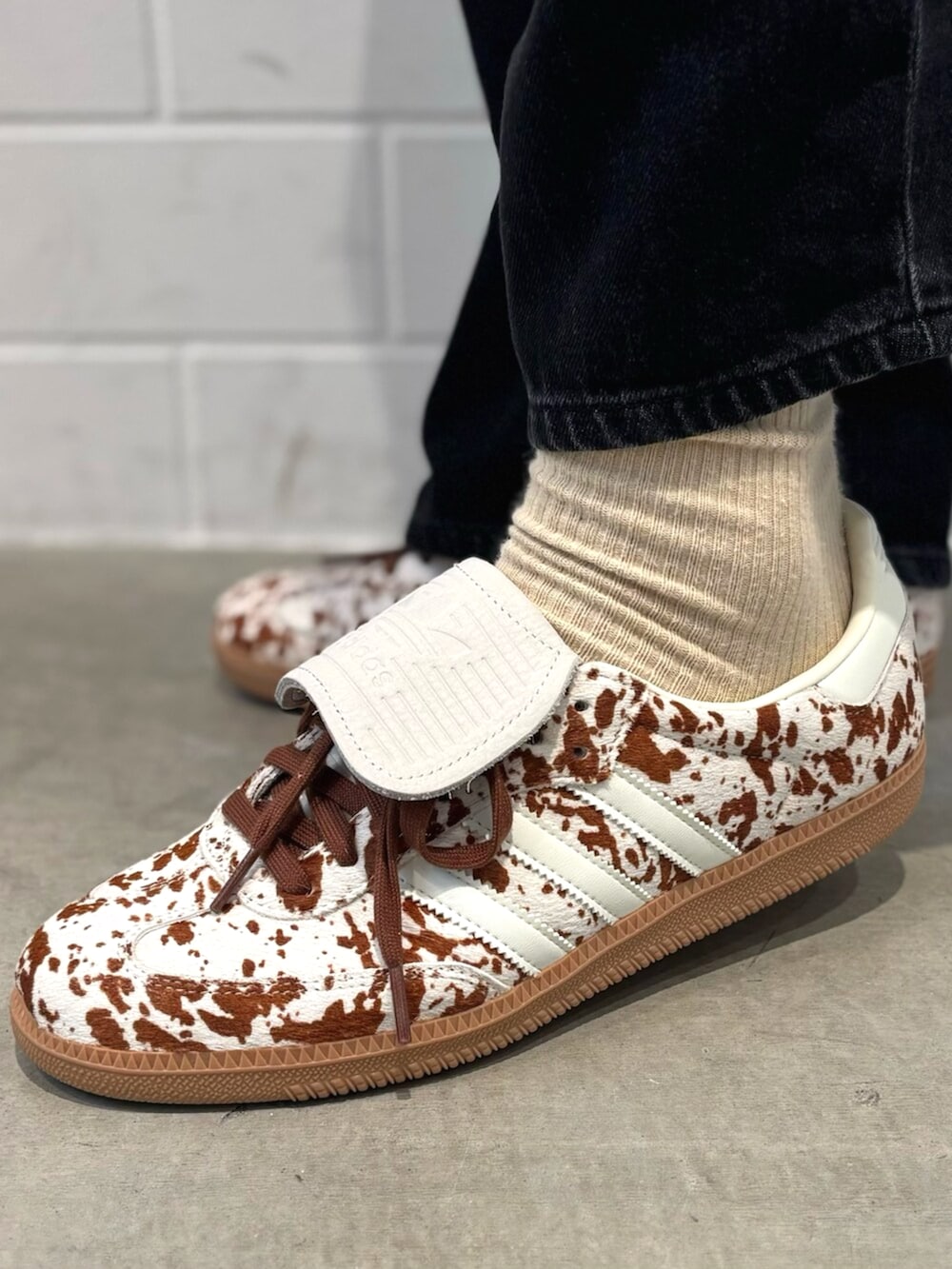 ホワイト系のスニーカー、ブラック系のニット/セーターを着用したメンズの秋コーディネートの4枚目の写真