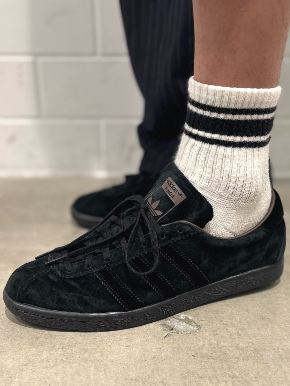 ホワイト系のポロシャツ、ブラック系のスニーカーを着用したメンズの秋コーディネートの4枚目の写真