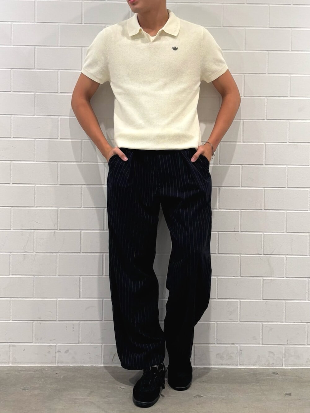 ホワイト系のポロシャツ、ブラック系のスニーカーを着用したメンズの秋コーディネートの2枚目の写真