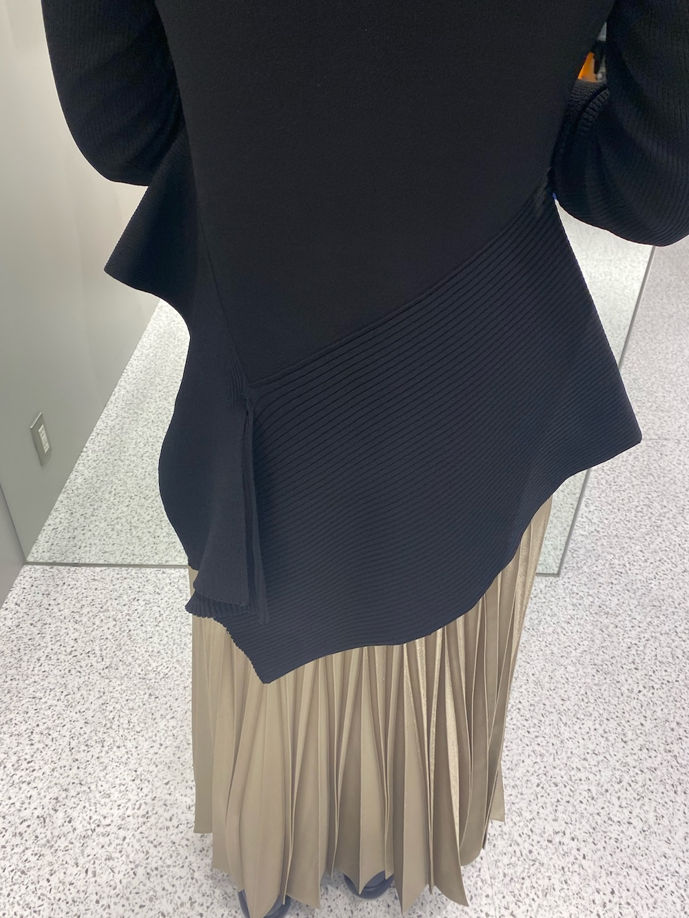 ブラック系のニット/セーター、ベージュ系のスカート、ブラック系のブーツを着用したレディースの春コーディネートの9枚目の写真