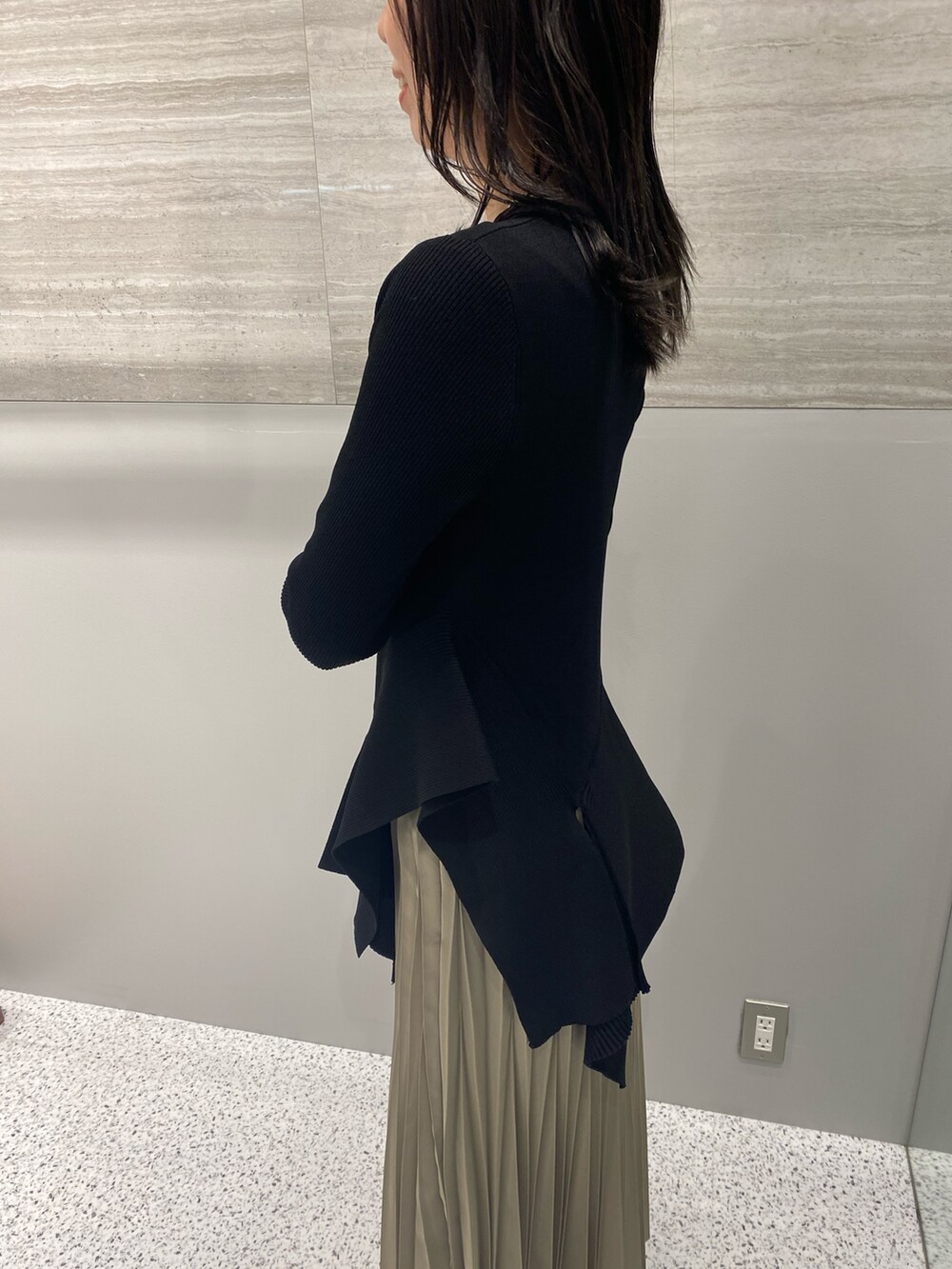 ブラック系のニット/セーター、ベージュ系のスカート、ブラック系のブーツを着用したレディースの春コーディネートの7枚目の写真