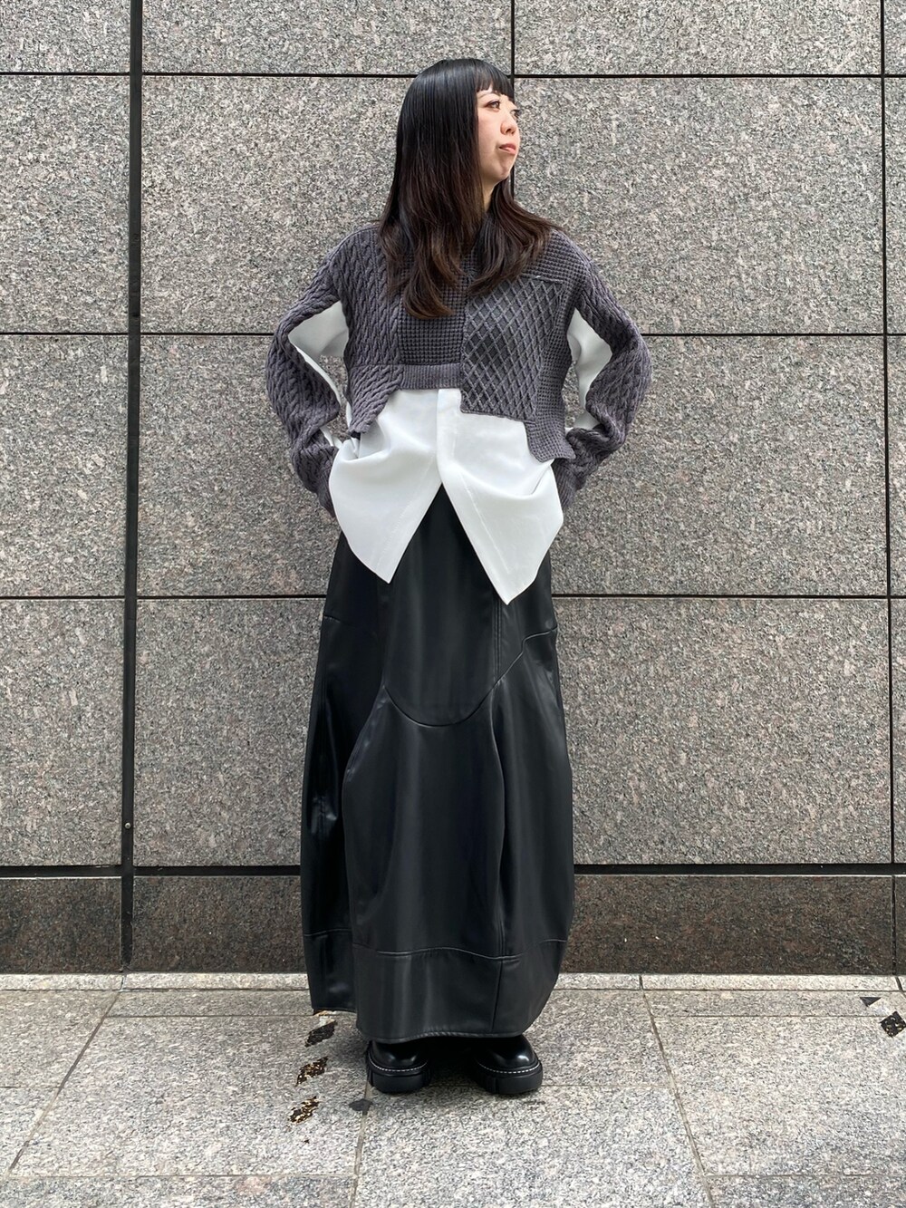 グレー系のニット/セーター、ブラック系のスカート、ブラック系のブーツを着用したレディースの秋コーディネートの2枚目の写真