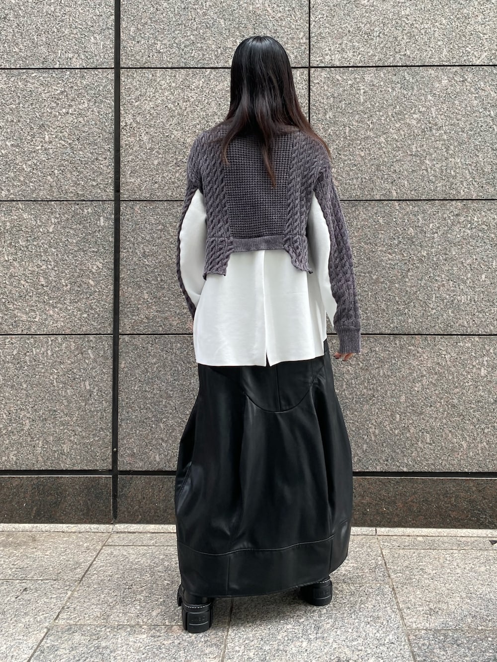 グレー系のニット/セーター、ブラック系のスカート、ブラック系のブーツを着用したレディースの秋コーディネートの4枚目の写真