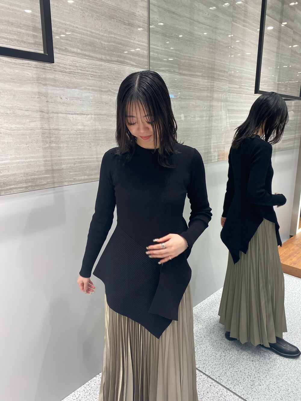 ブラック系のニット/セーター、ベージュ系のスカート、ブラック系のブーツを着用したレディースの春コーディネートの6枚目の写真