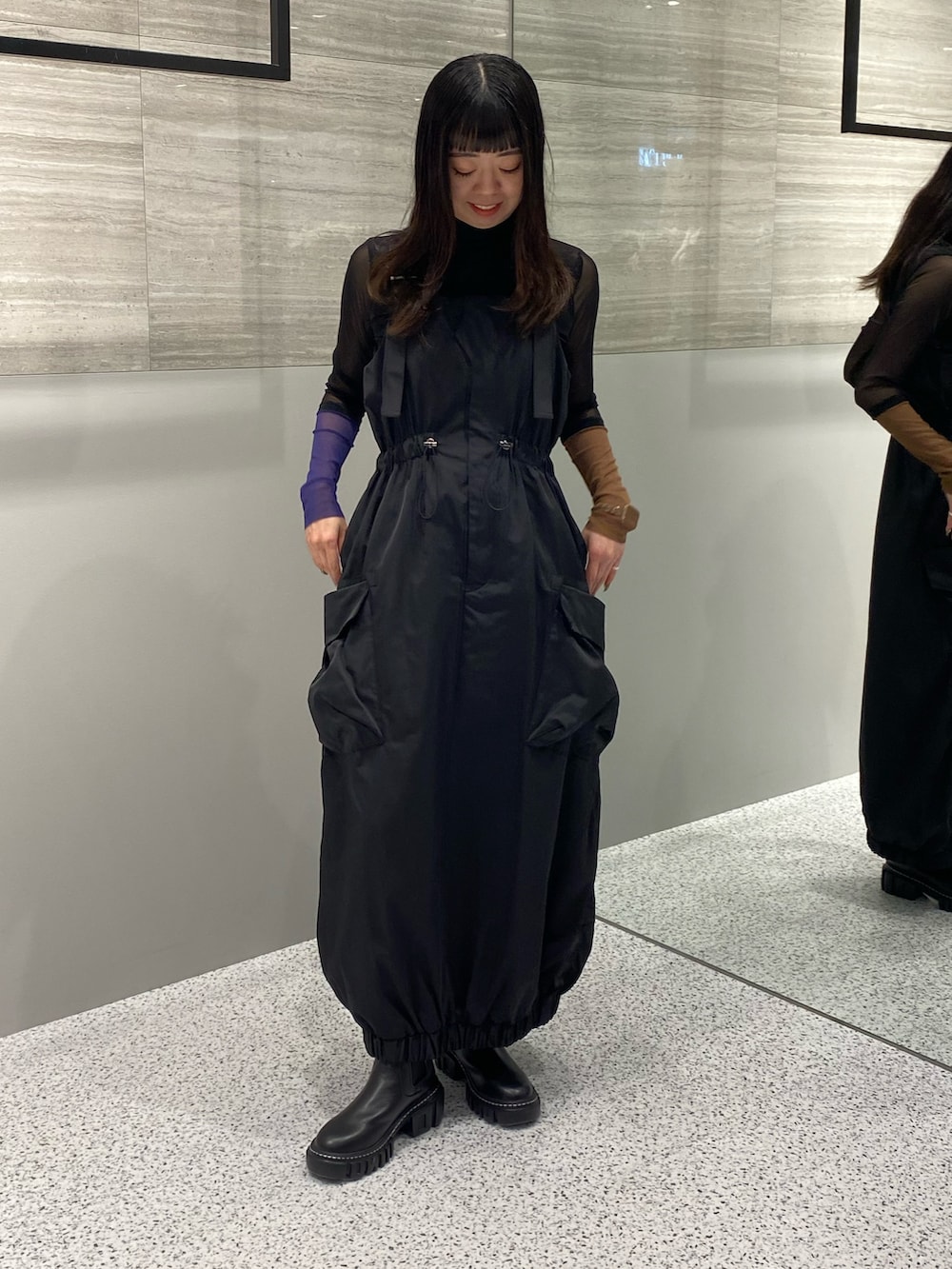 ブラック系のワンピース、ブラック系のTシャツ/カットソー、ブラック系のブーツを着用したレディースの秋コーディネートの2枚目の写真