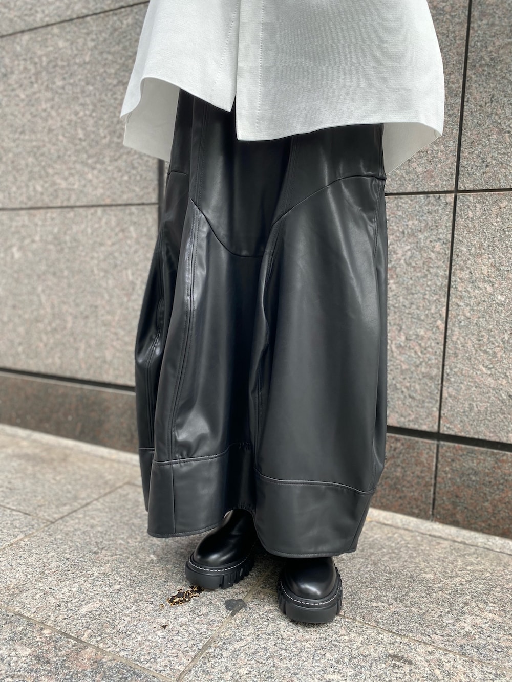 グレー系のニット/セーター、ブラック系のスカート、ブラック系のブーツを着用したレディースの秋コーディネートの7枚目の写真