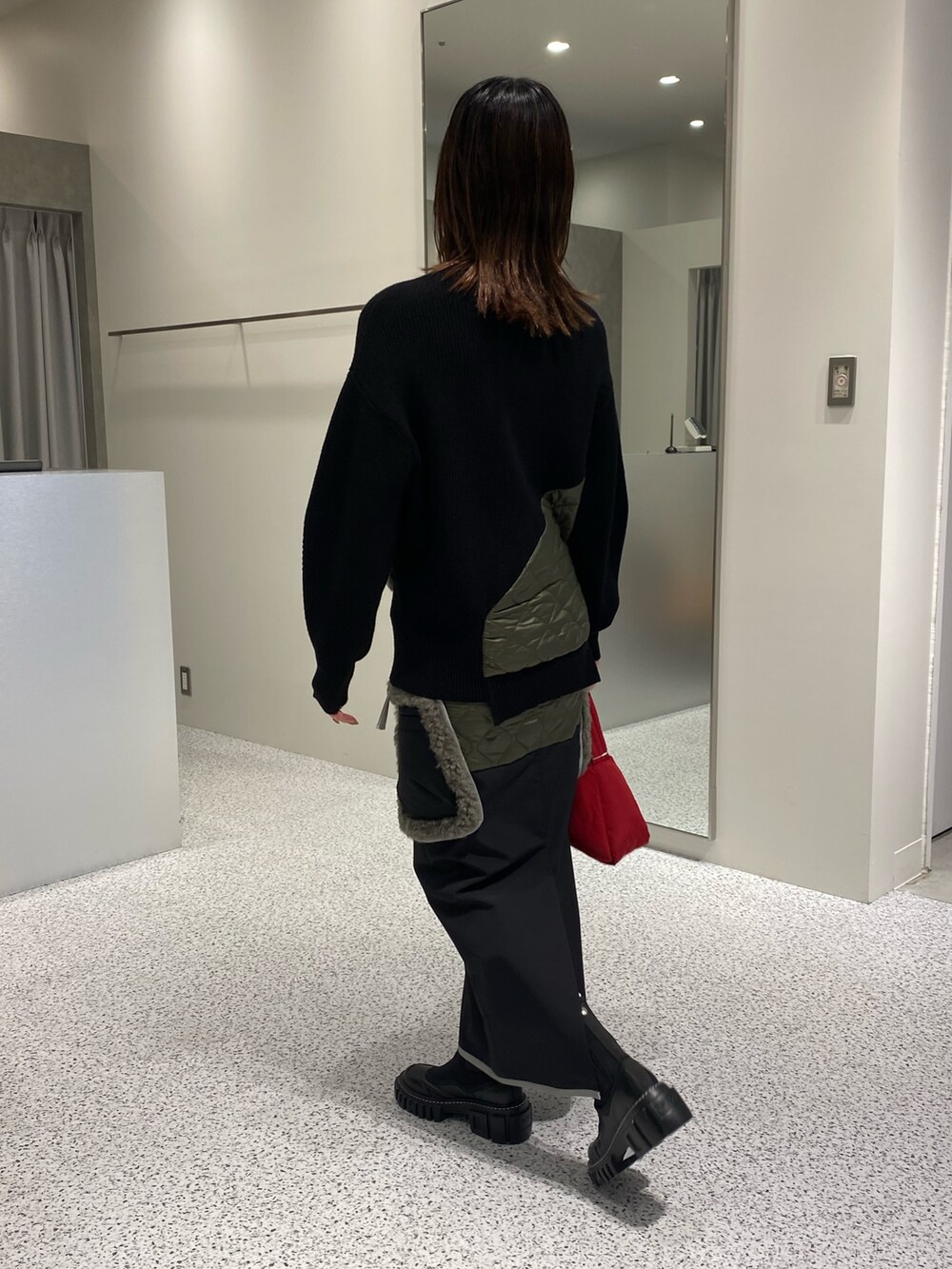 ブラック系のニット/セーター、ブラック系のスカート、レッド系のハンドバッグを着用したレディースの秋コーディネートの4枚目の写真