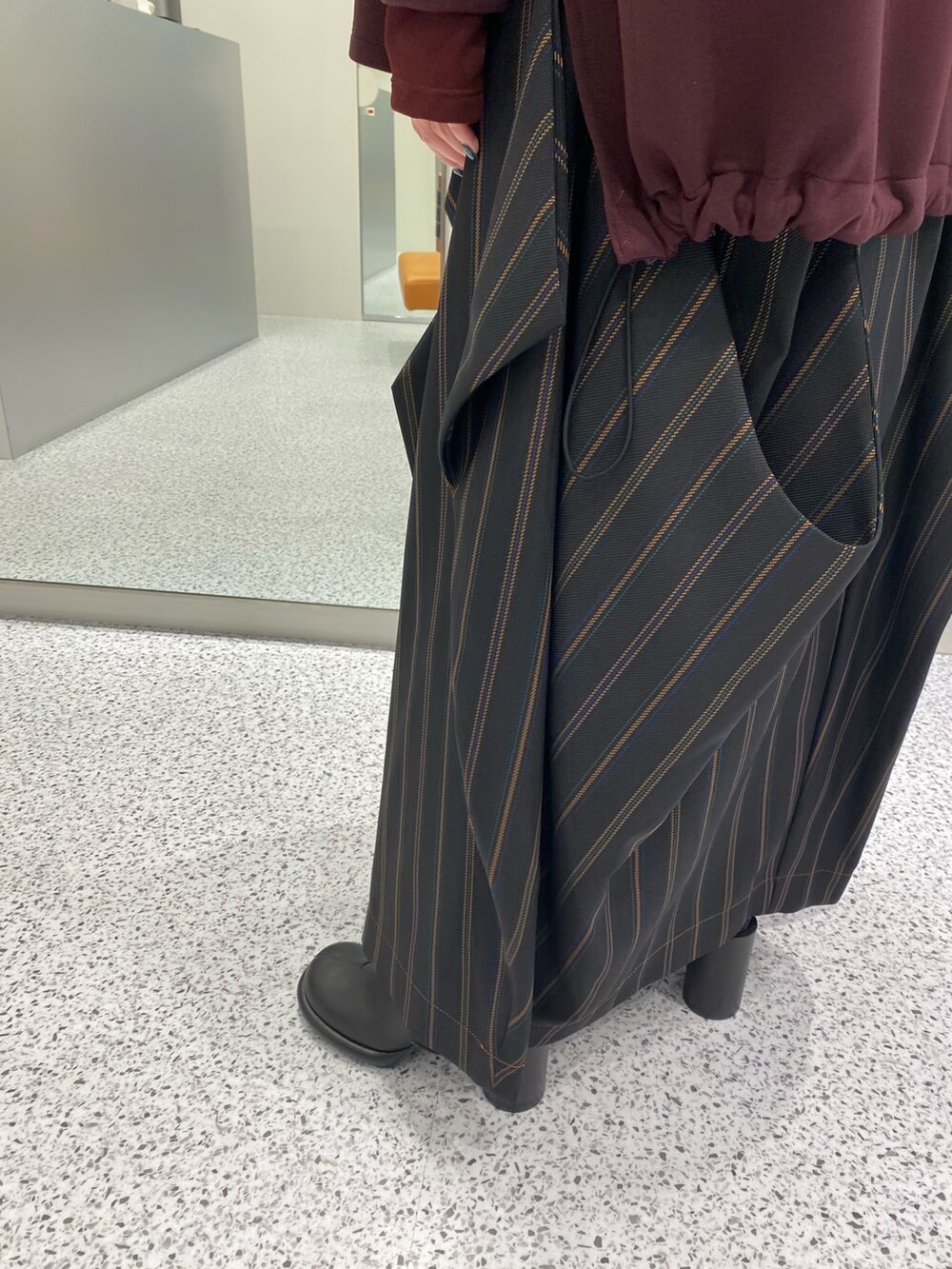 ブラウン系のパーカー、ブラック系のスカート、ブラック系のブーツを着用したレディースの秋コーディネートの8枚目の写真