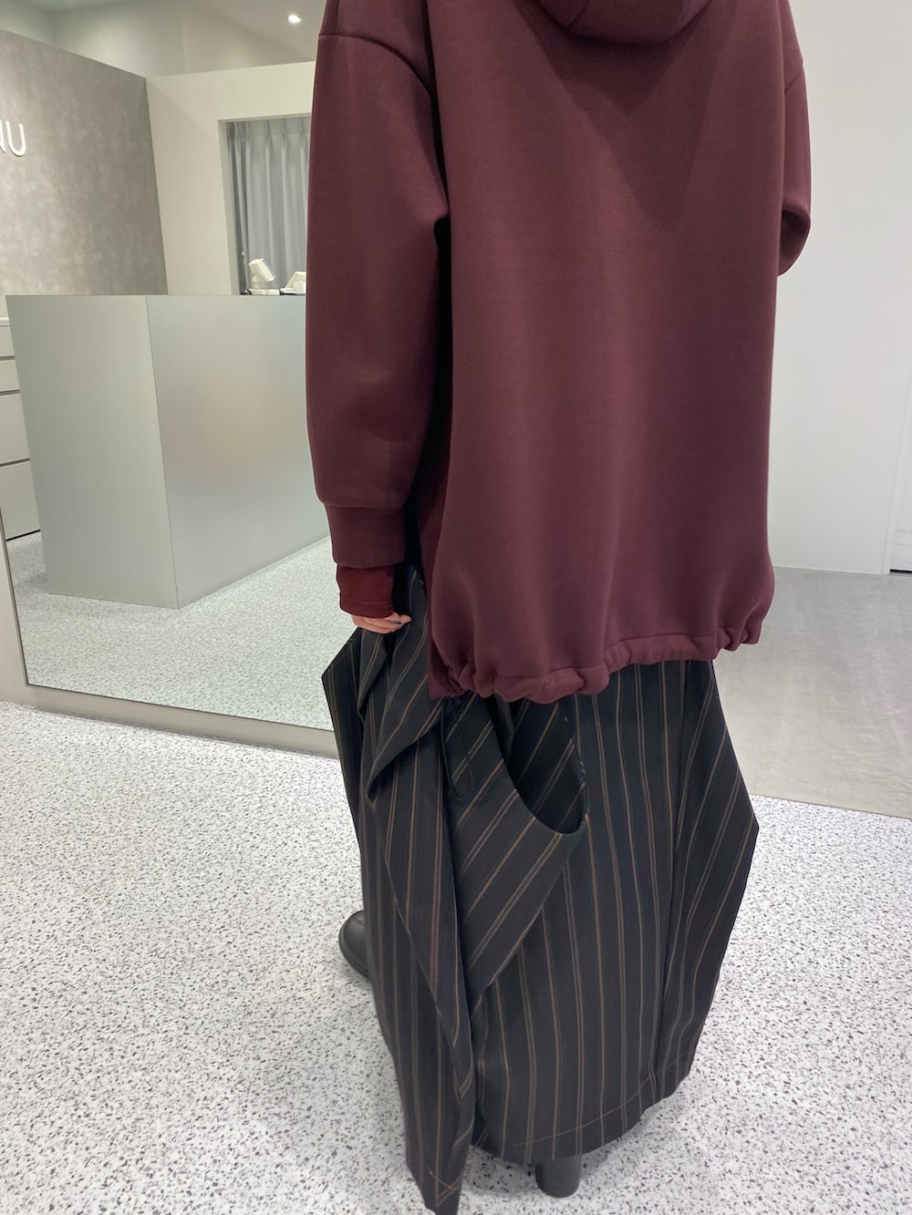 ブラウン系のパーカー、ブラック系のスカート、ブラック系のブーツを着用したレディースの秋コーディネートの5枚目の写真