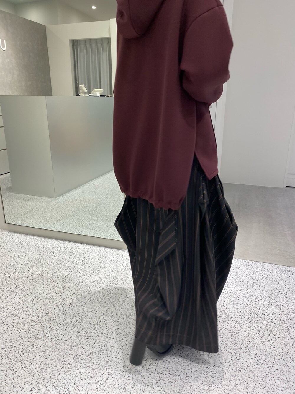 ブラウン系のパーカー、ブラック系のスカート、ブラック系のブーツを着用したレディースの秋コーディネートの6枚目の写真