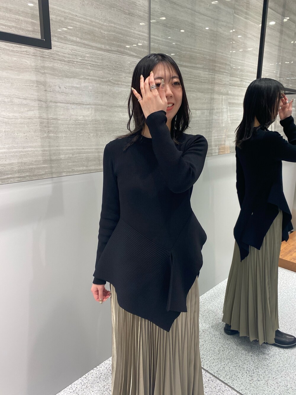 ブラック系のニット/セーター、ベージュ系のスカート、ブラック系のブーツを着用したレディースの春コーディネートの5枚目の写真