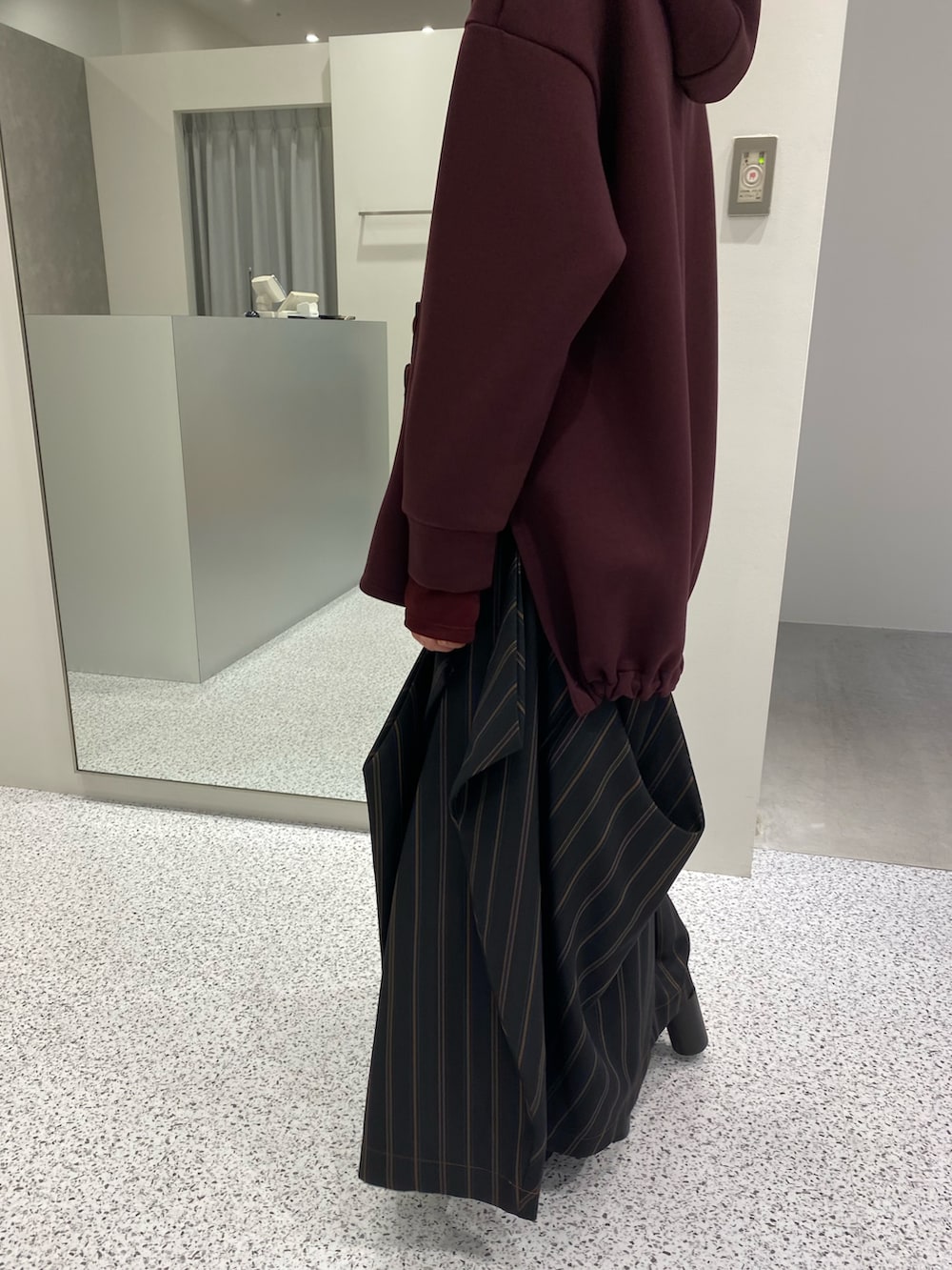 ブラウン系のパーカー、ブラック系のスカート、ブラック系のブーツを着用したレディースの秋コーディネートの3枚目の写真