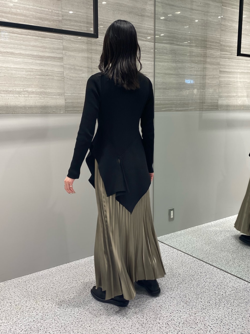 ブラック系のニット/セーター、ベージュ系のスカート、ブラック系のブーツを着用したレディースの春コーディネートの4枚目の写真