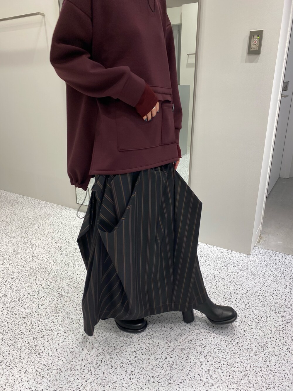 ブラウン系のパーカー、ブラック系のスカート、ブラック系のブーツを着用したレディースの秋コーディネートの7枚目の写真