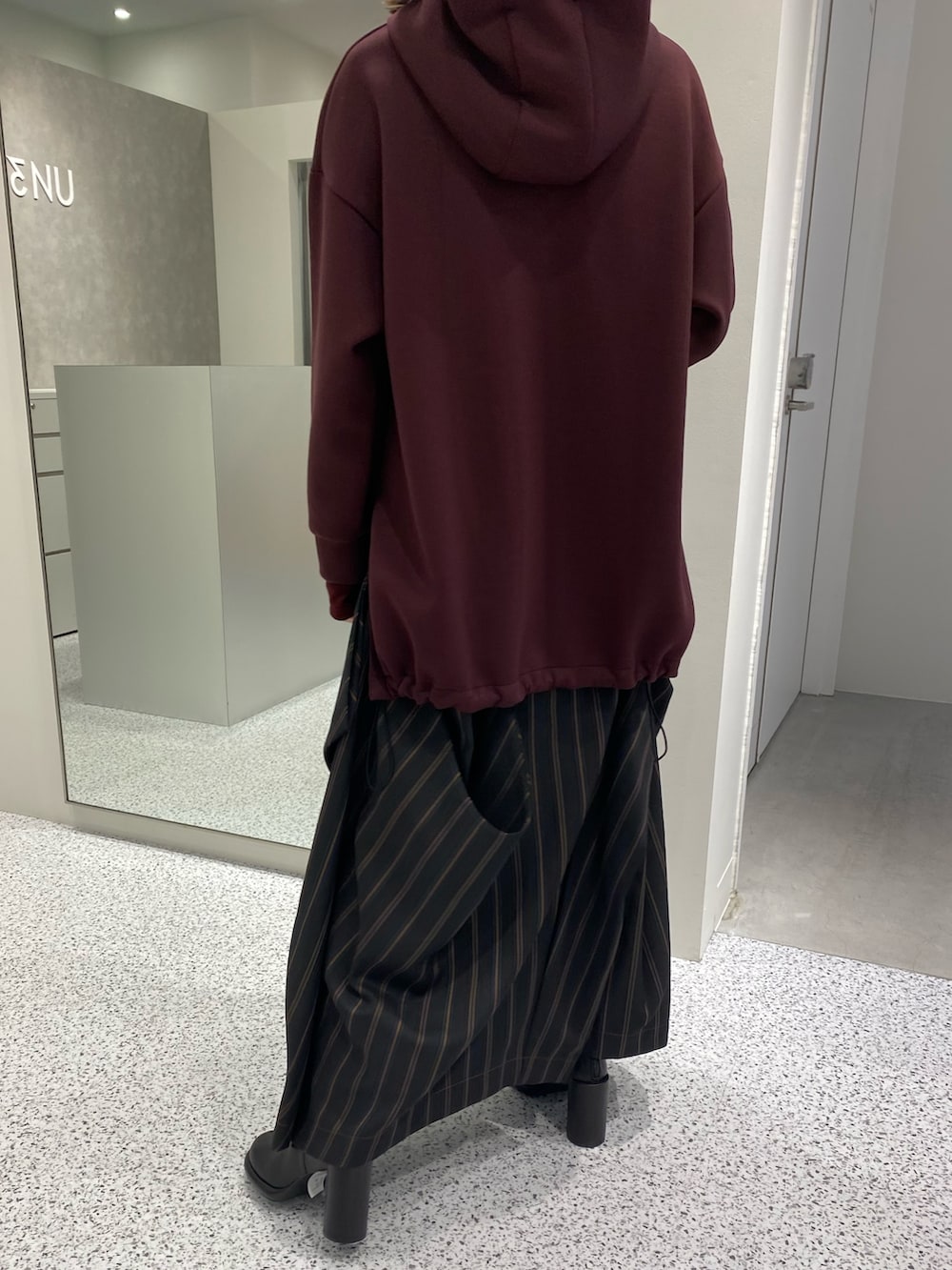 ブラウン系のパーカー、ブラック系のスカート、ブラック系のブーツを着用したレディースの秋コーディネートの4枚目の写真