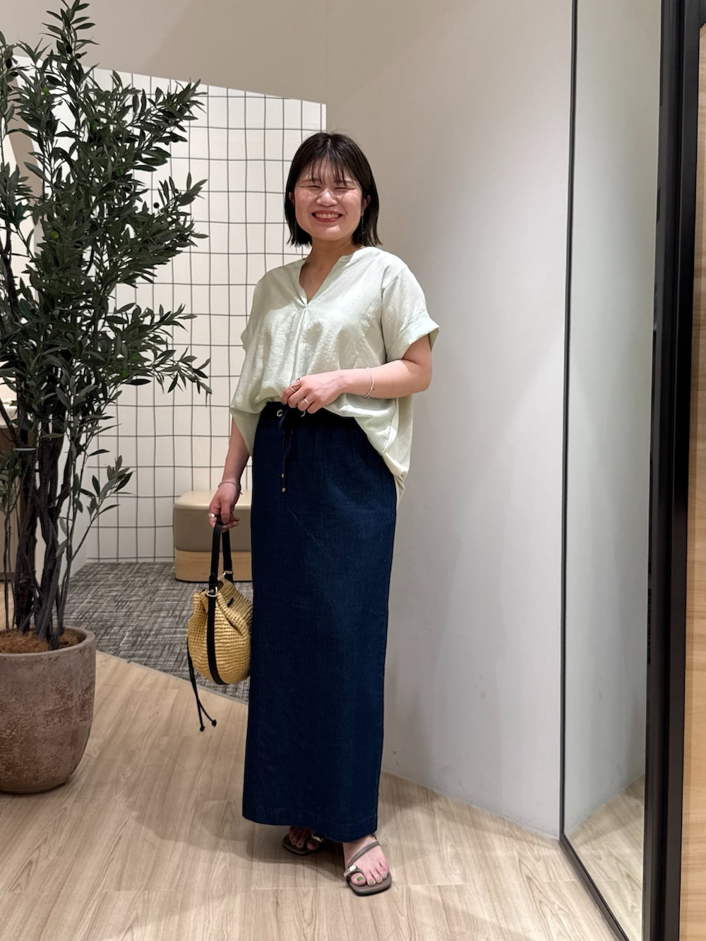 ブルー系のスカート、グリーン系のシャツ/ブラウス、ベージュ系のトートバッグを着用したレディースの夏コーディネートの2枚目の写真