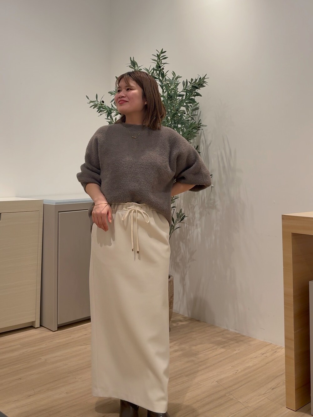 ホワイト系のダウンジャケット/コート、ブラウン系のニット/セーター、ホワイト系のスカートを着用したレディースの秋コーディネートの2枚目の写真