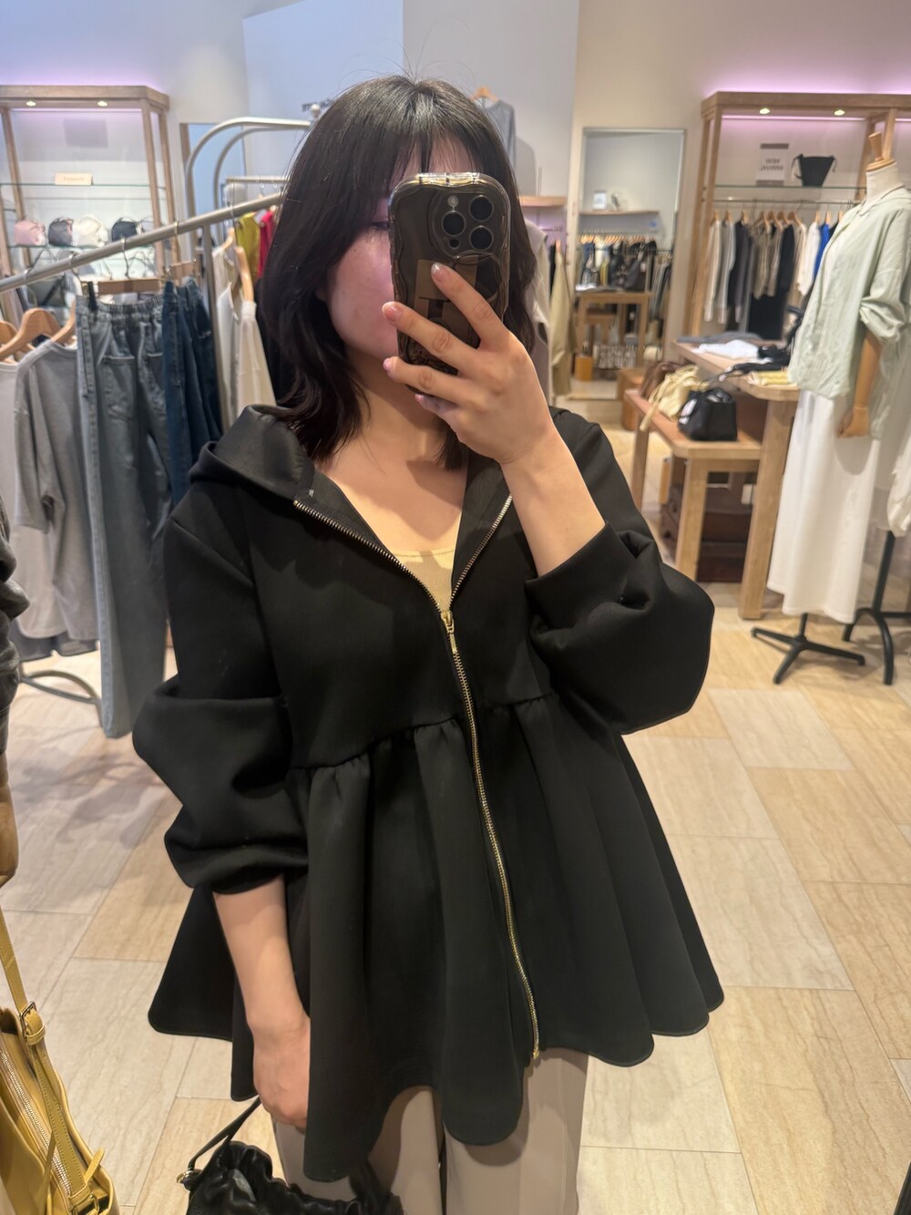 ブラック系のパーカー、ベージュ系のその他パンツ、ブラック系のトートバッグを着用したレディースの春コーディネートの2枚目の写真