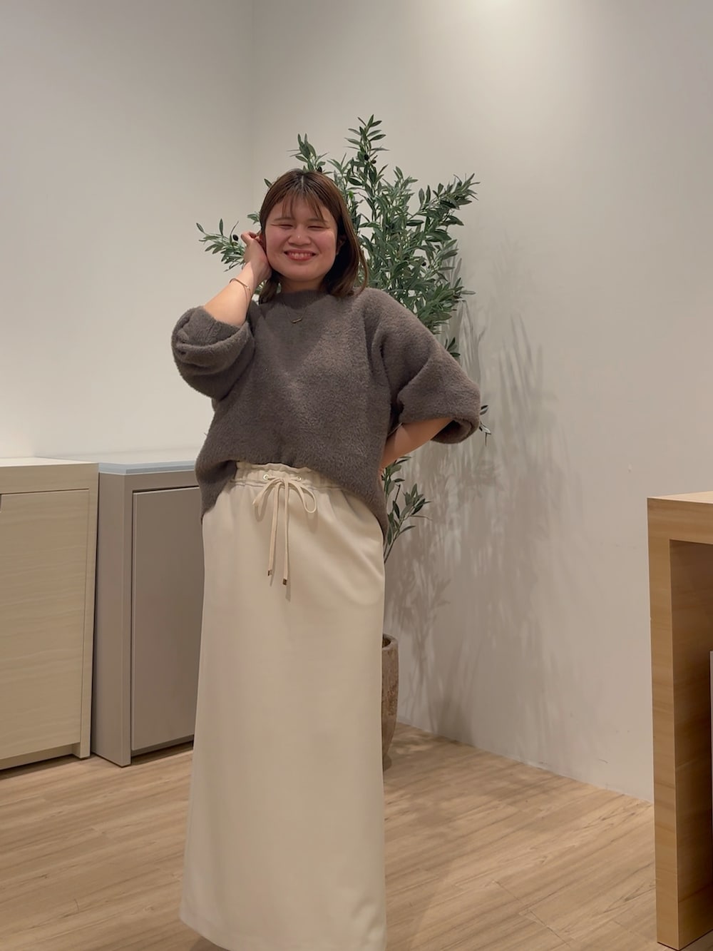 ホワイト系のダウンジャケット/コート、ブラウン系のニット/セーター、ホワイト系のスカートを着用したレディースの秋コーディネートの3枚目の写真