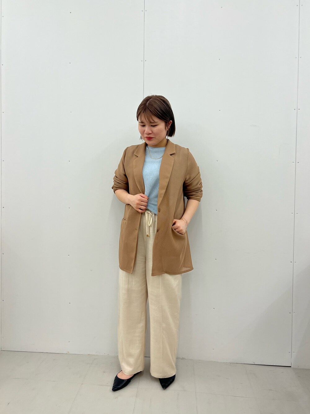 ベージュ系のテーラードジャケット、ブルー系のニット/セーター、ベージュ系のその他パンツを着用したレディースの春コーディネートの2枚目の写真