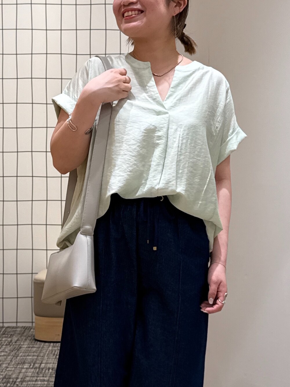 ブルー系のデニムパンツ、グリーン系のシャツ/ブラウス、グレー系のショルダーバッグを着用したレディースの夏コーディネートの3枚目の写真