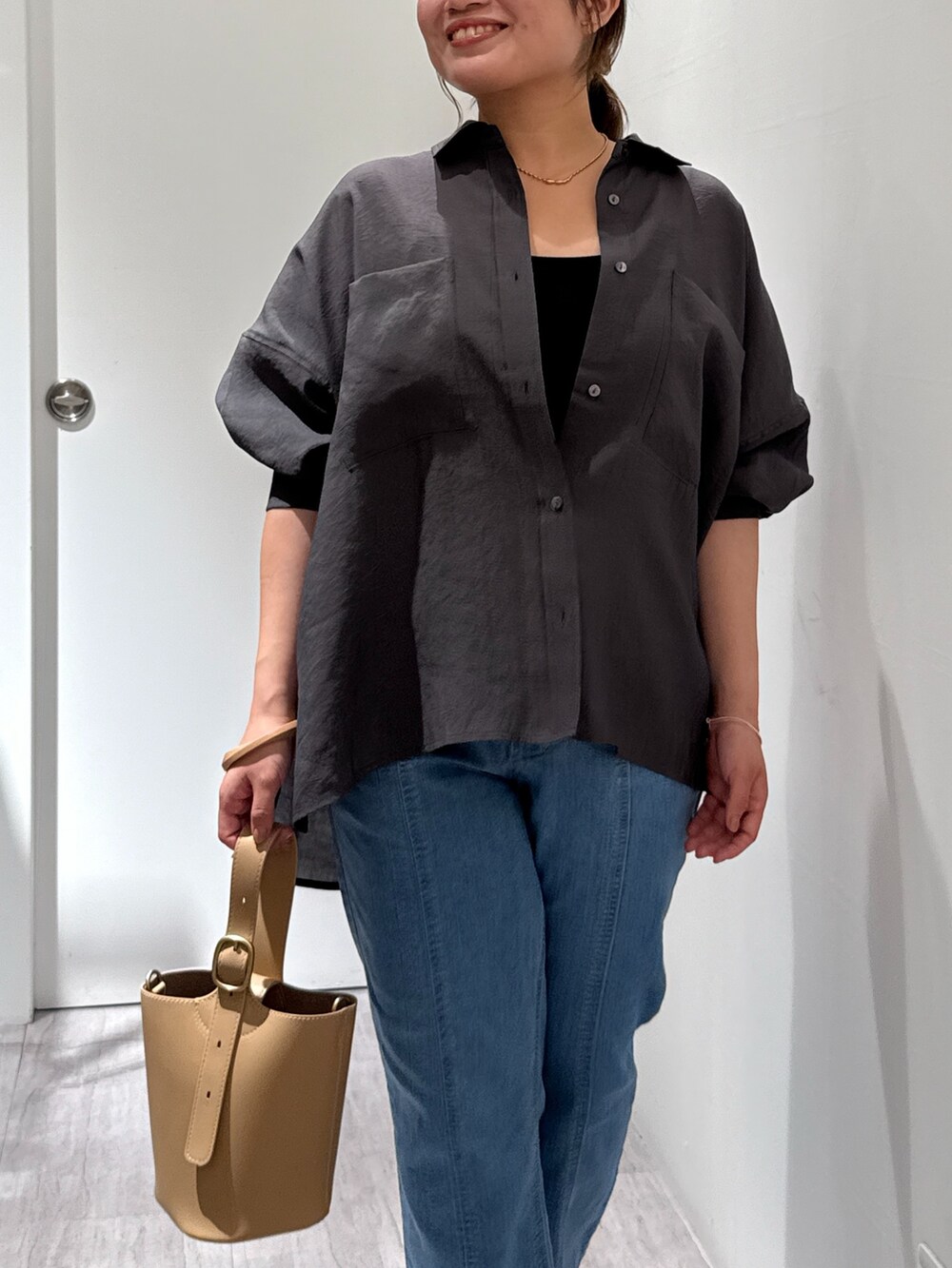 グレー系のシャツ/ブラウス、ブルー系のデニムパンツ、ベージュ系のショルダーバッグを着用したレディースの夏コーディネートの3枚目の写真