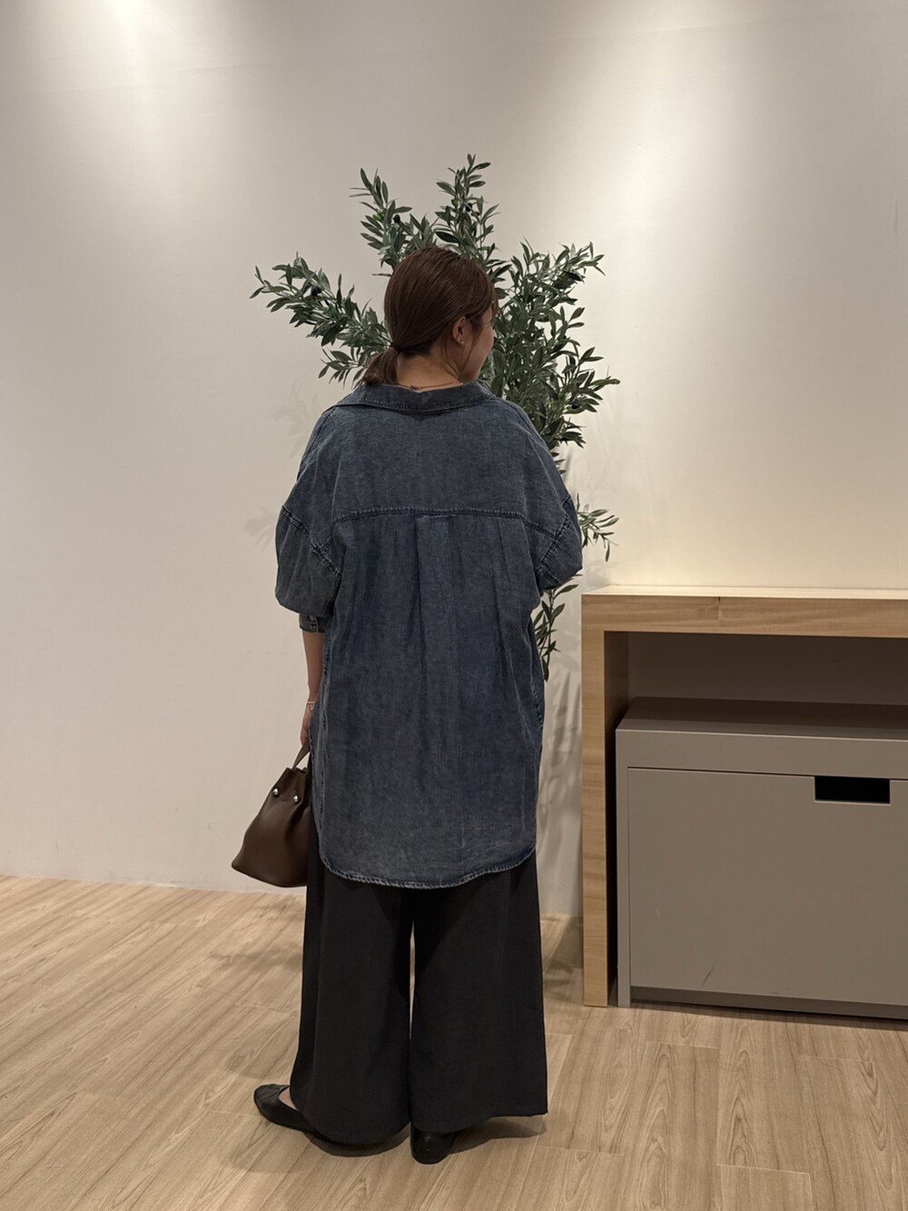 ブルー系のシャツ/ブラウス、ブラウン系のトートバッグ、ブラック系のその他パンツを着用したレディースの秋コーディネートの3枚目の写真