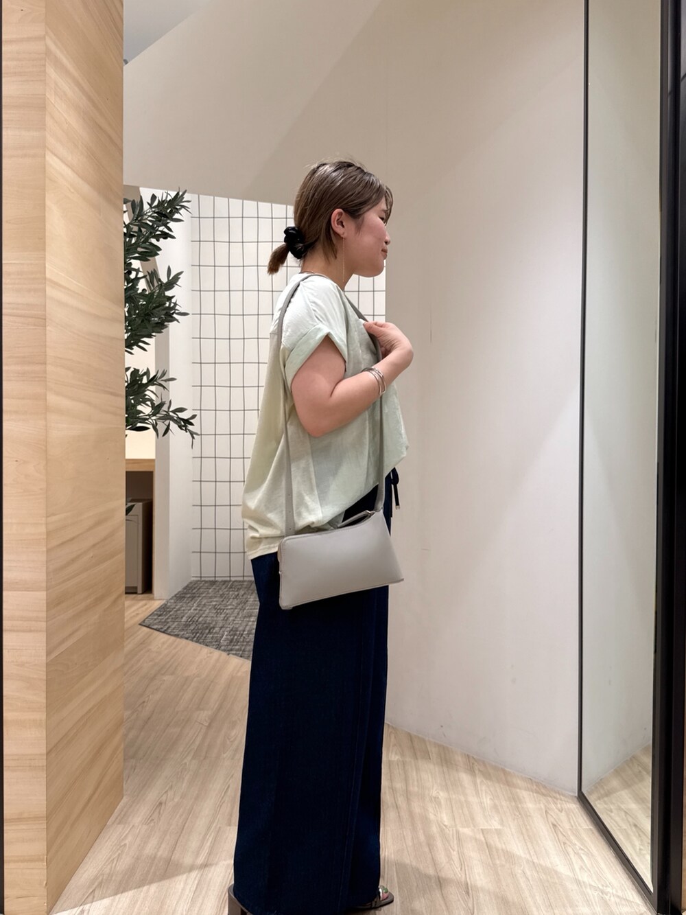 ブルー系のデニムパンツ、グリーン系のシャツ/ブラウス、グレー系のショルダーバッグを着用したレディースの夏コーディネートの4枚目の写真