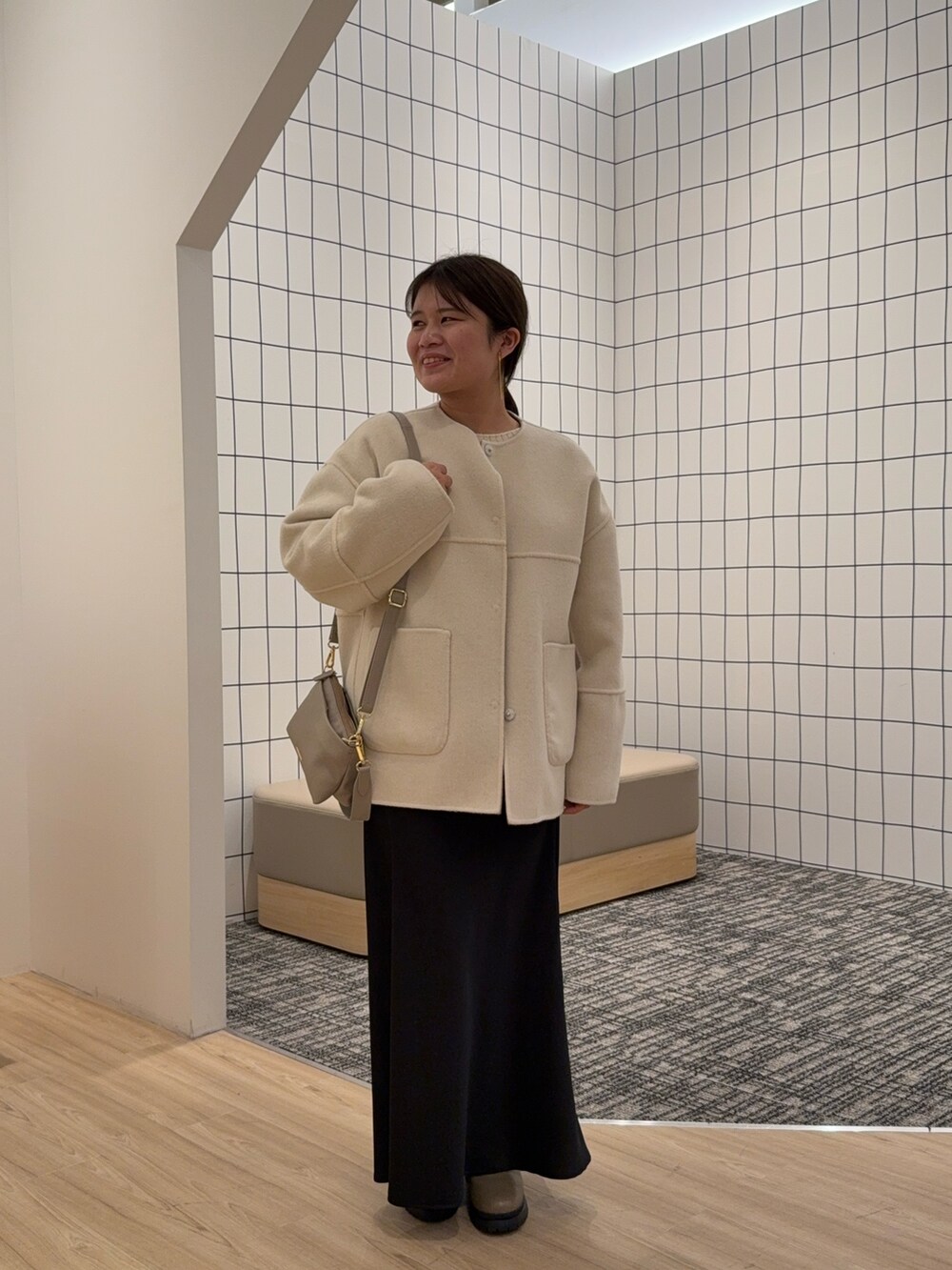 ベージュ系のノーカラージャケット、ブラック系のスカートを着用したレディースの秋コーディネートの2枚目の写真