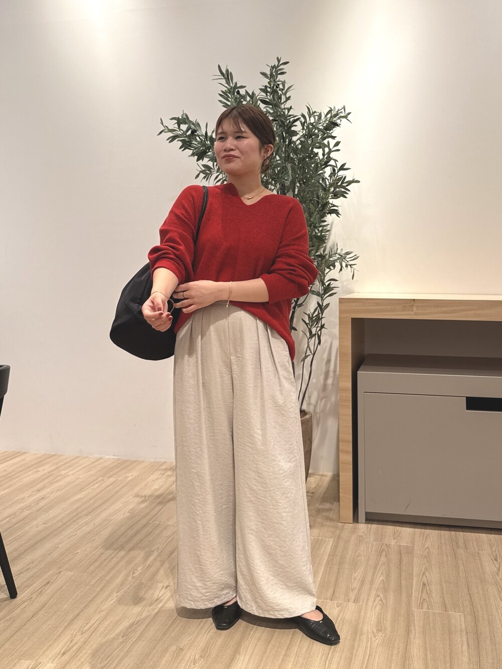 グレー系のその他パンツ、レッド系のニット/セーター、ブラック系のパンプスを着用したレディースの秋コーディネートの2枚目の写真