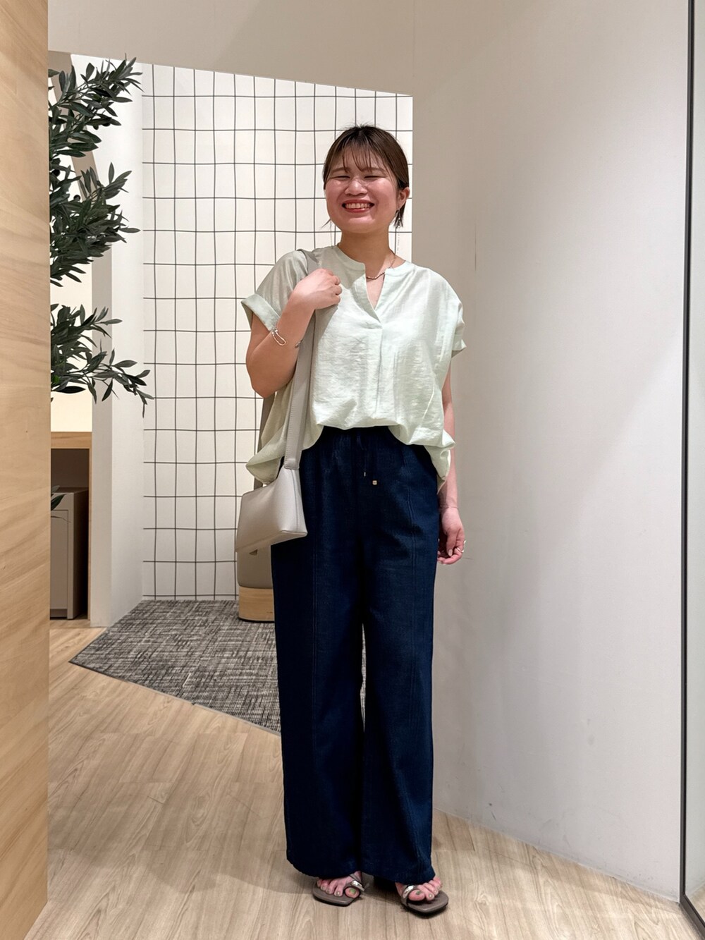 ブルー系のデニムパンツ、グリーン系のシャツ/ブラウス、グレー系のショルダーバッグを着用したレディースの夏コーディネートの2枚目の写真