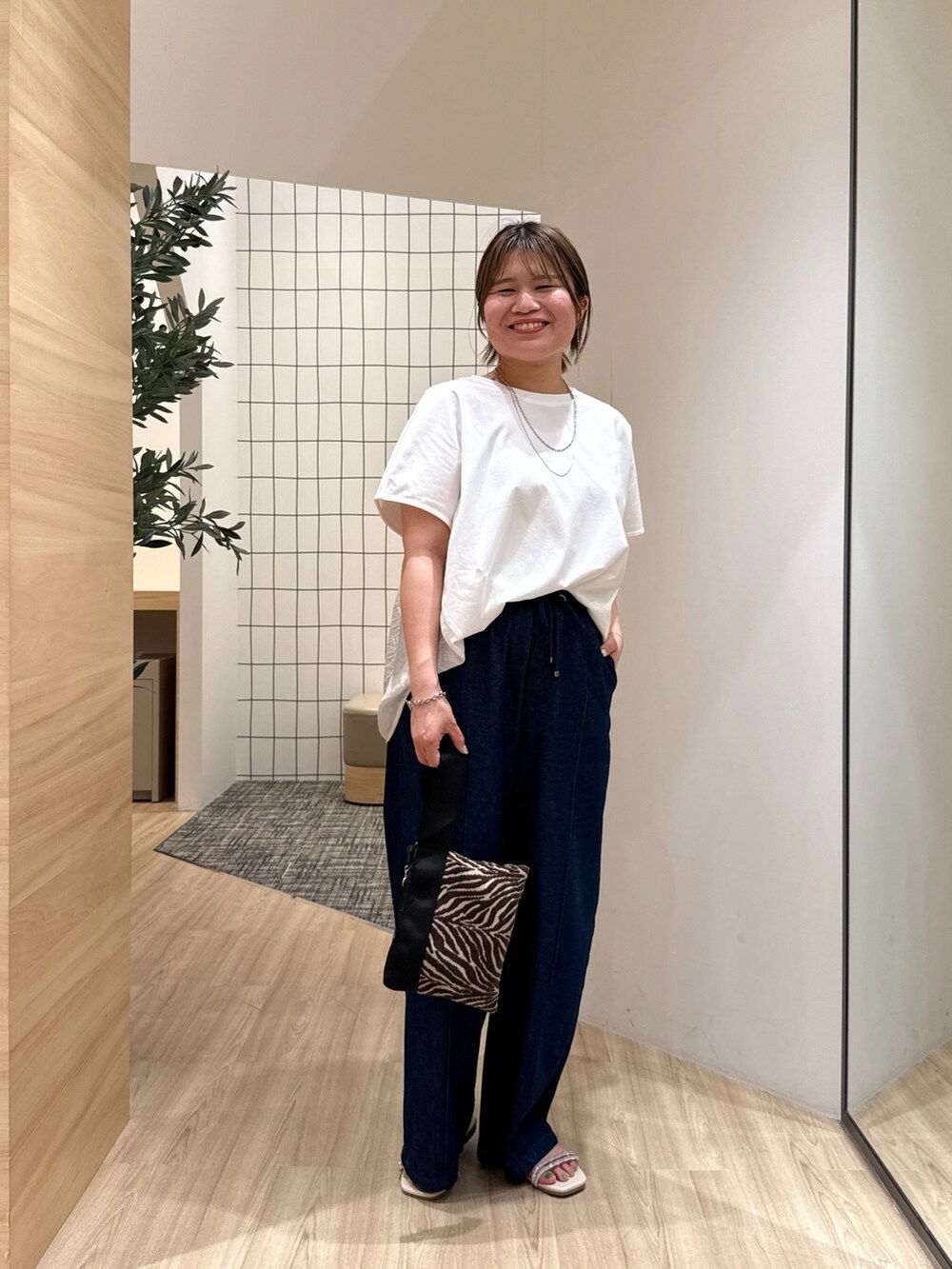 ブルー系のデニムパンツ、ホワイト系のTシャツ/カットソー、ホワイト系のサンダルを着用したレディースの夏コーディネートの2枚目の写真