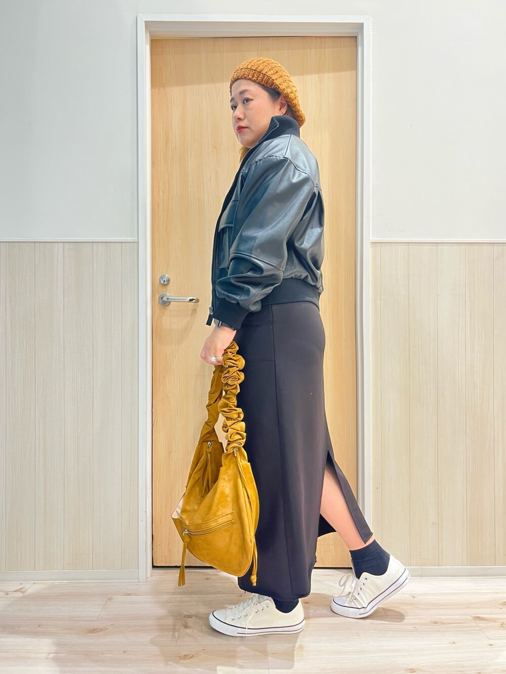 ブラック系のスカート、ブラック系のブルゾン、イエロー系のニット/セーターを着用したレディースの秋コーディネートの2枚目の写真