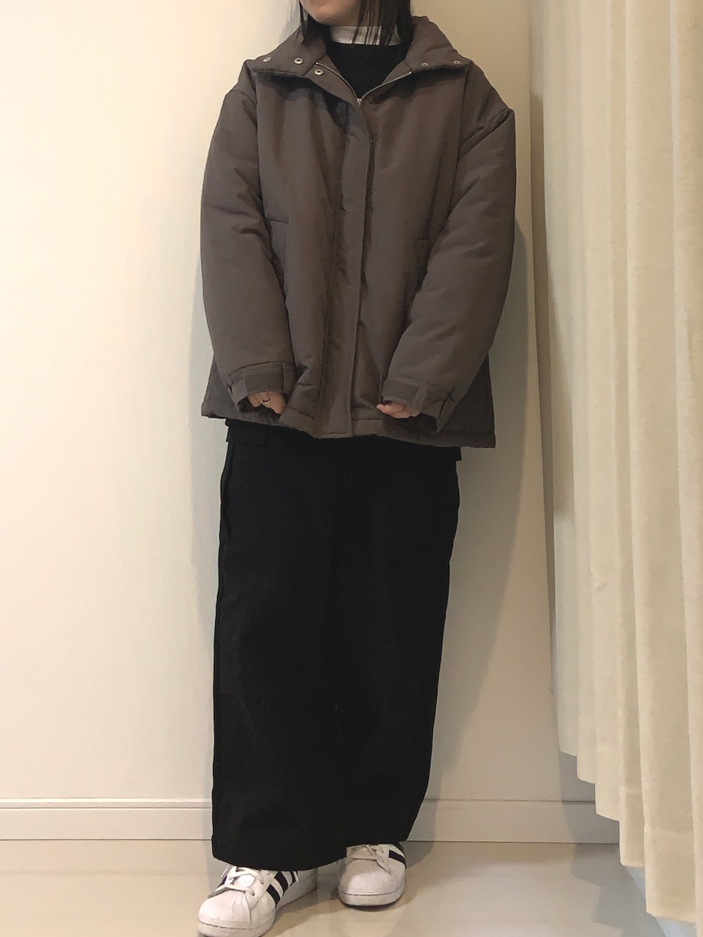 ブラック系のカーゴパンツ、ブラック系のスウェット、ホワイト系のスニーカーを着用したレディースの冬コーディネートの2枚目の写真