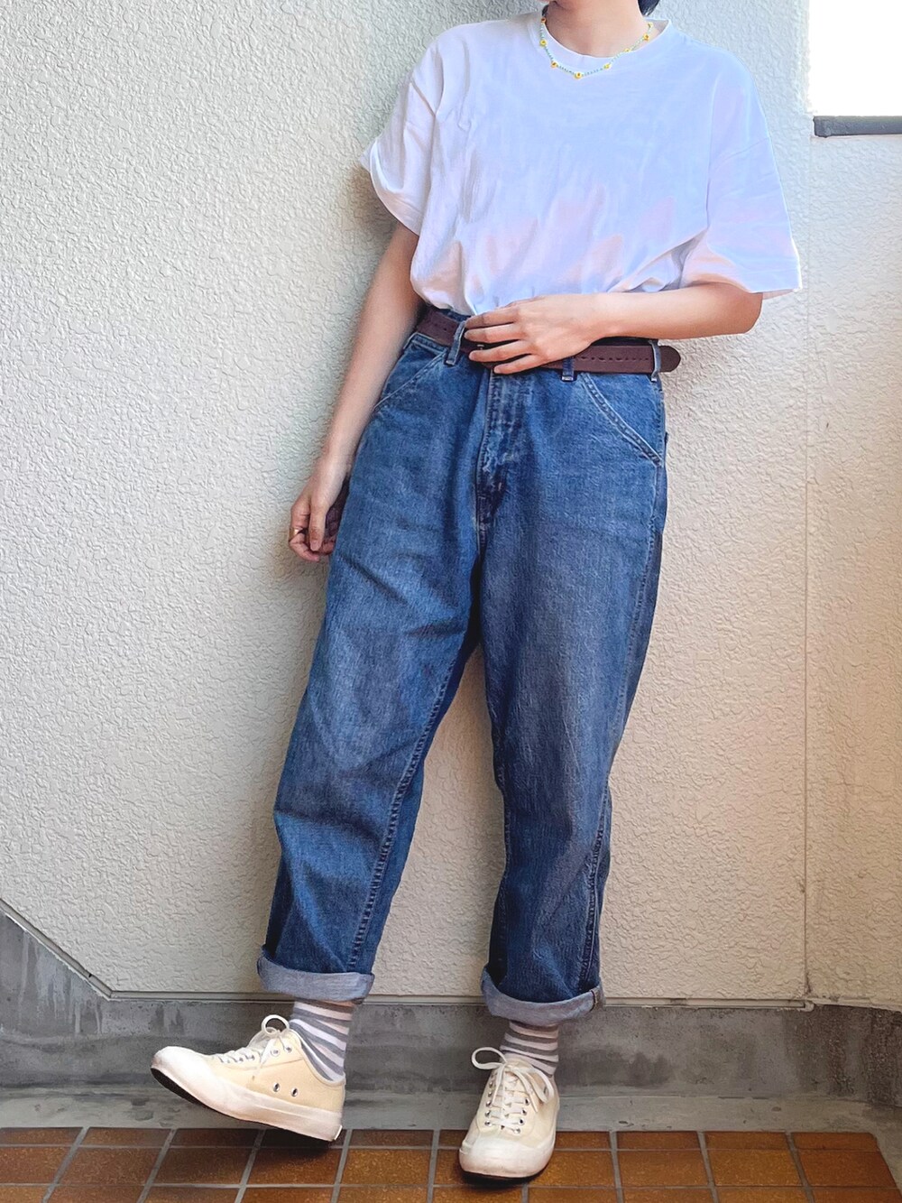 ホワイト系のTシャツ/カットソー、ブルー系のデニムパンツ、イエロー系のスニーカーを着用したレディースの春コーディネートの2枚目の写真