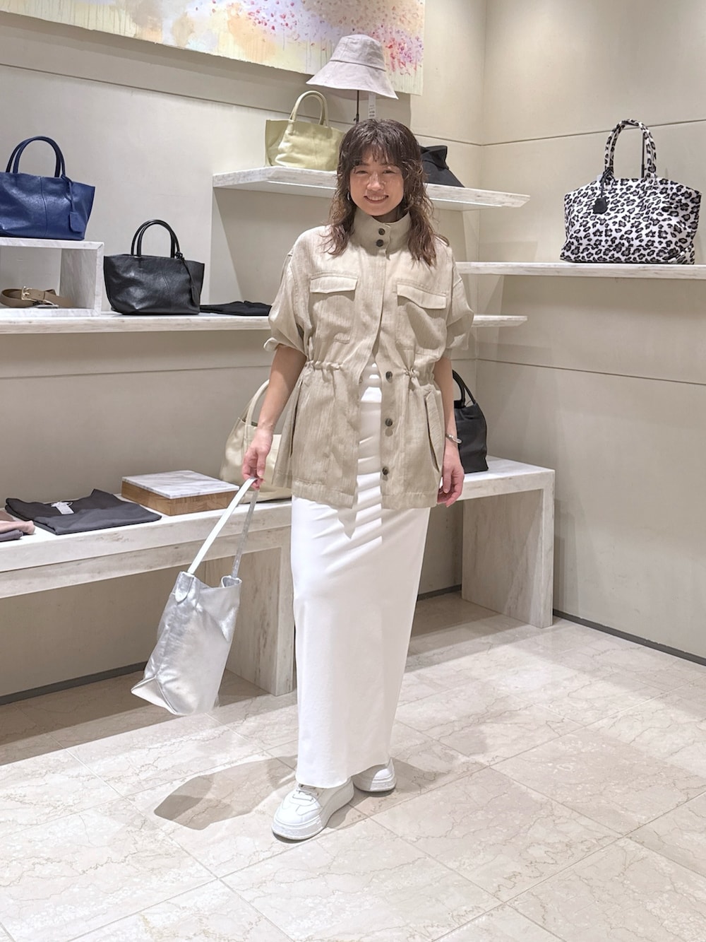 グリーン系のベスト、ホワイト系のスカート、シルバー系のトートバッグを着用したレディースの春コーディネートの4枚目の写真