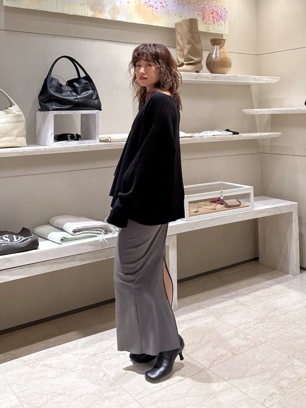 ブラック系のニット/セーター、グレー系のスカート、ブラック系のブーツを着用したレディースの冬コーディネートの2枚目の写真