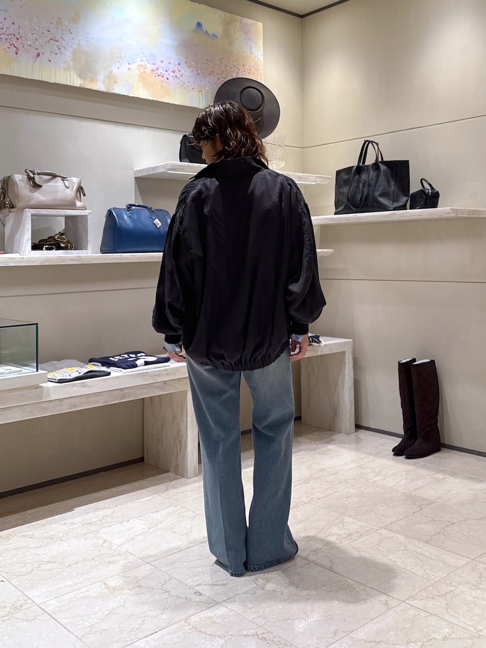 ブルー系のデニムパンツ、ブラック系のブーツ、ブラック系のトートバッグを着用したレディースの秋コーディネートの3枚目の写真