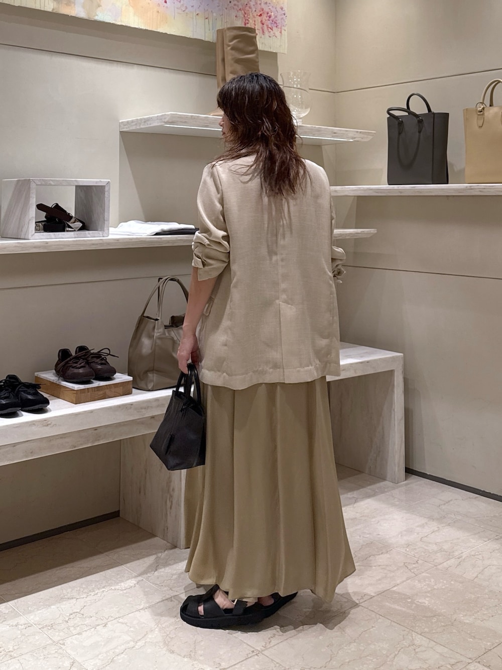 ベージュ系のスカート、ブラック系のトートバッグ、ブラック系のサンダルを着用したレディースの春コーディネートの3枚目の写真