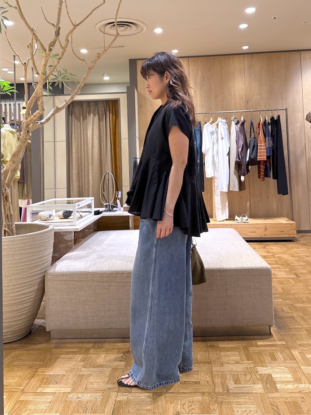 ブルー系のデニムパンツ、ブラック系のサンダル、グリーン系のトートバッグを着用したレディースの夏コーディネートの2枚目の写真